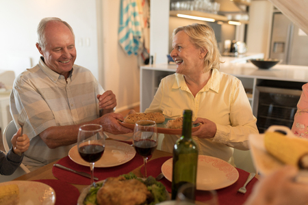 Side view of a senior couple interacting with each other on dining table at homeの写真素材