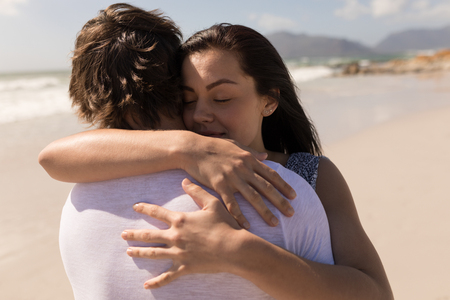 Closeup of a romantic young couple embracing each other on beach in the sunshineの写真素材