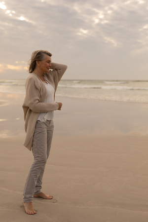 Side view of senior Caucasian woman standing with eyes closed on the beach at beachの写真素材