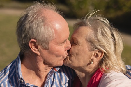 Front view of active senior Caucasian couple kissing each other in the park