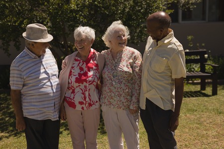 Front view of happy senior friends interacting with each other in gardenの写真素材