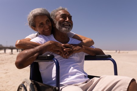 Front view of woman embracing disabled senior man on beach in the sunshineの写真素材