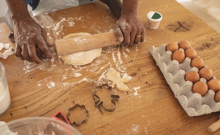 High angle view of African American father and son rolling dough with rolling pin in kitchen at home
