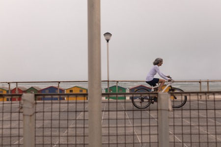 Side view of senior woman riding bicycle on promenade at beach