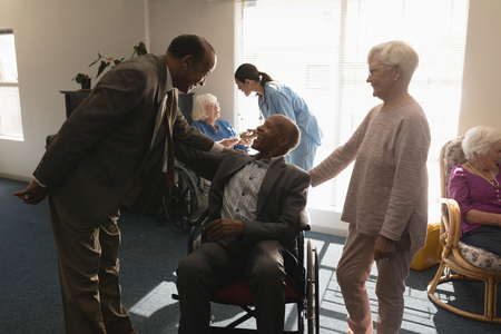 Front view of senior friends interacting with each other at nursing homeの写真素材