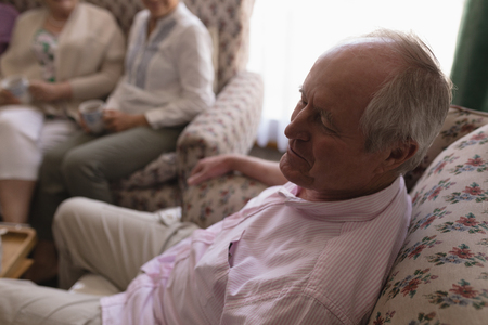Side view of active senior man relaxing in living room on sofa at homeの写真素材