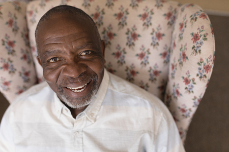 Portait of smiling active senior man relaxing on sofa in living room at home