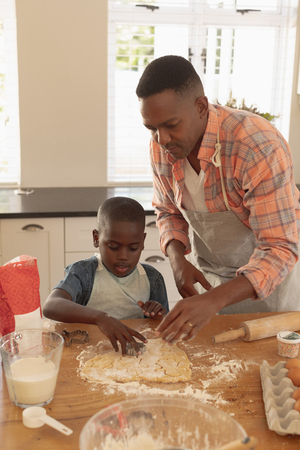 Front view of African American father and son baking cookies in kitchen at homeの写真素材