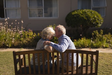 Rear view of active senior Caucasian man kissing senior Caucasian woman in the parkの写真素材
