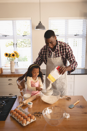 High angle view of African American father and daughter baking cookies in kitchen at homeの写真素材