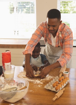 Front view of African American father and son baking cookies in kitchen at homeの写真素材