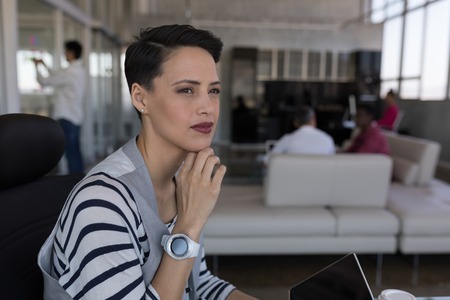 Side view of beautiful mixed-race female executive looking thoughtful while working in modern office