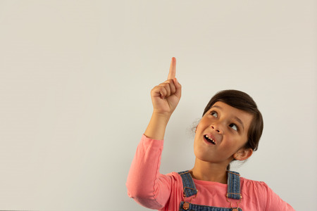 Front view of thoughtful mixed-race girl pointing his finger up against white background