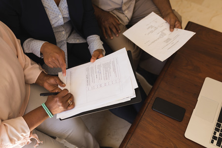 Overhead view of a senior African American woman signing property contract with real estate agent...