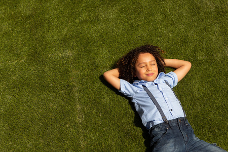 High angle view of a mixed-race schoolgirl relaxing in the school playground on a sunny dayの写真素材