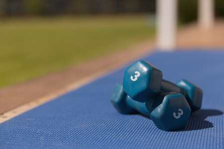 Close-up of blue dumbbells kept on a blue exercise matの写真素材