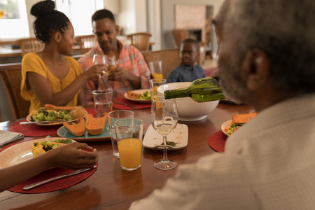 Rear view of a multi-generation family having wine on dining table at home
