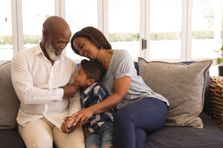 Front view of a happy multi-generation African American family sitting on sofa in living room at homeの写真素材