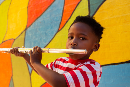 Portrait of African American schoolboy playing flute instrument in the school playgroundの写真素材
