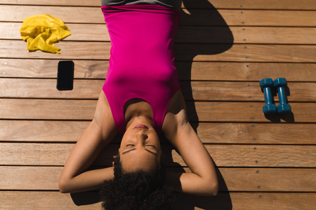 Overhead view of a tired woman relaxing in the backyard after fitness at homeの写真素材
