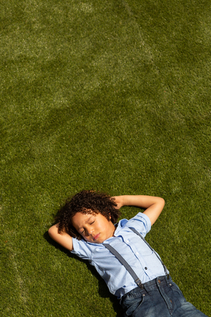 High angle view of a mixed-race schoolgirl relaxing in the school playground on a sunny dayの写真素材