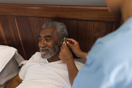 High angle view of a young African American female doctor fitting a senior African American man with...