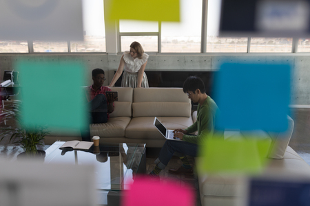 Front view of diverse male and female executives discussing business plans over digital tablet and laptop in modern officeの写真素材