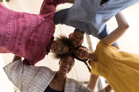 Low angle view of diverse business colleagues smiling while forming huddle in officeの写真素材