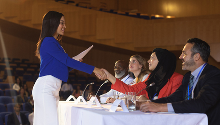 Side view of young mixed race business woman shaking hand to the business colleague in the...
