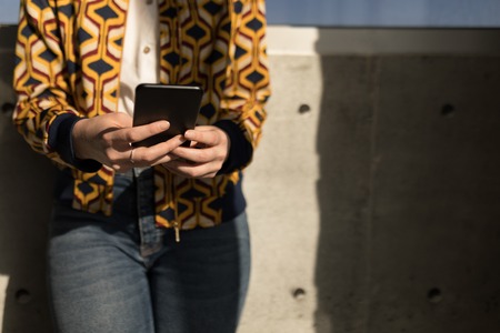 Mid section of young Caucasian female executive using mobile phone in modern officeの写真素材