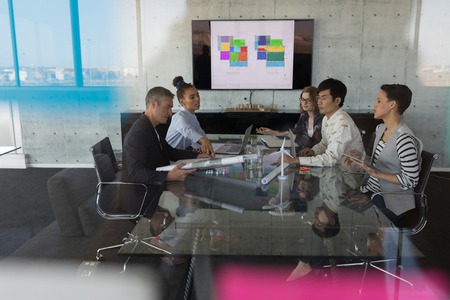 High view of sitting mixed race business people having discussion in a meeting at modern office....
