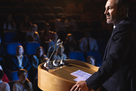 Side view of Caucasian businessman standing on a stage of auditorium for presentationの写真素材