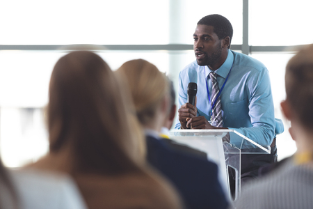Side view of African-American businessman speaker speaking in a business seminar in modern office buildingの写真素材