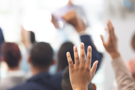 Close-up of multi-ethnic hands being raised in a business seminar in office buildingの写真素材
