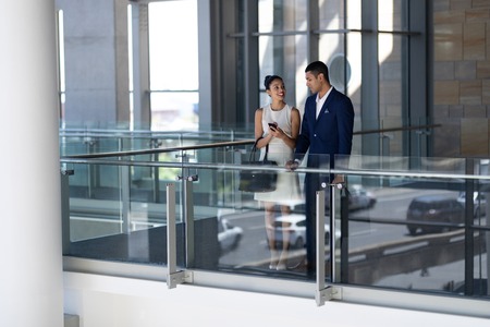 Front view of elegant young mixed-race business people interacting with each other standing in modern officeの写真素材
