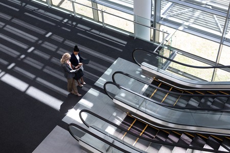 High angle view of young multi-ethnic businesswomen discussing over digital tablet in modern office