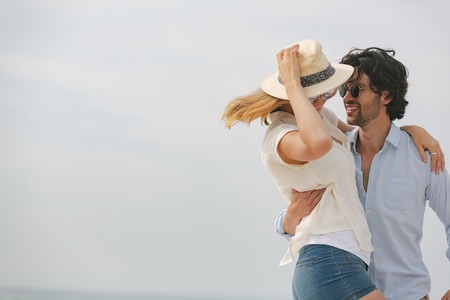 Side view of happy young Caucasian couple looking at each other and dancing on beach on sunny day. They are smilingの写真素材