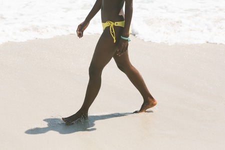Low section of African-american woman walking on beach on a sunny dayの写真素材