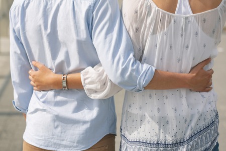 Mid section of Caucasian couple standing on the promenade with arm around on a sunny dayの写真素材