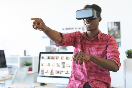 Front view of young African-American graphic designer using virtual reality headset in officeの写真素材