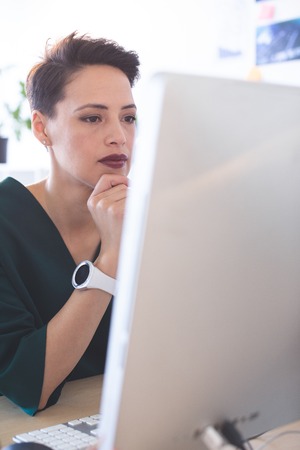 Front view of beautiful Mixed-race female executive working on computer at desk in the officeの写真素材