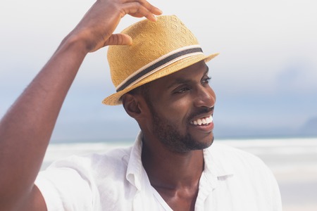 Portrait of happy African American man standing at beach while looking away from the camera on a sunny day. He is smilingの写真素材