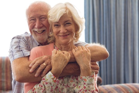 Portrait of happy Caucasian senior couple sitting on sofa at retirement homeの写真素材