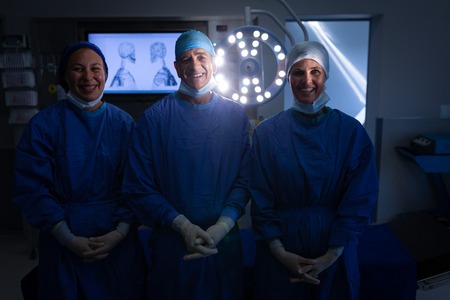 Front view of Caucasian surgeons smiling to the camera with hands crossed in the operation theater...