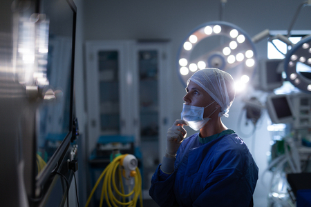 Side view of a Caucasian female surgeon looking at surgical monitor in operation theaterの写真素材
