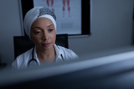 Front view of matured mixed race female doctor working on computer in clinic at hospital