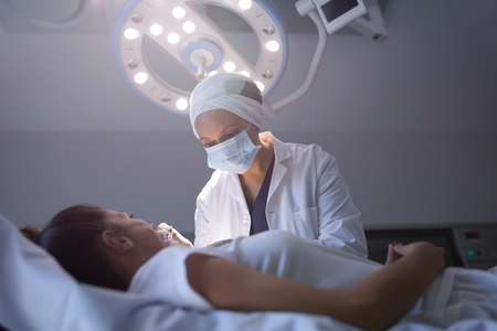 Low angle view of a mature mixed race female dentist examining a Caucasian patient in a clinicの写真素材