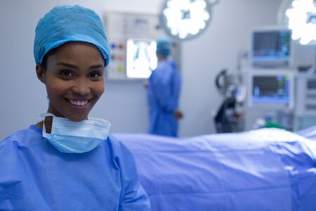 Front view of happy Mixed-race female surgeon sitting in operation theater at hospitalの写真素材