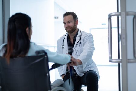 Front view of Caucasian male doctor consoling female patient in the corridor at hospitalの写真素材