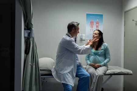 Front view of Caucasian male doctor examining a pregnant Caucasian woman on table of examination room in the hospitalの写真素材